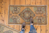 Visible distressed texture on a vintage Oushak runner with geometric medallion in beige and silver tones.