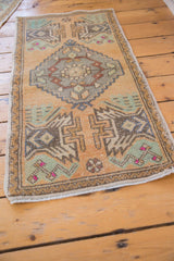 Distressed Oushak rug corner showing geometric plants, primitive pink buds, and intact selvage.