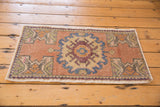 Distressed Oushak rug corner showing even wear on geometric floral motifs in sandlewood and pale green.