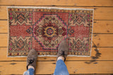Distressed Oushak rug with stepped diamond medallion in blush, pink, and silver tones.