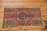Distressed Oushak rug corner: geometric planter motif, dusty blush tones, and faint foundation.