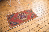 Distressed vintage Oushak runner with an oversized central medallion, brick red field, and time-softened pile.