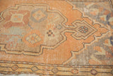 Distressed Oushak rug close-up, showing worn pile with apricot, sandlewood, and slate blue tones.