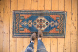 Close-up of the distressed Oushak rug's central medallion with pomegranate and checker motifs.