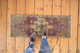Distressed Oushak runner with faded dusty purple and seafoam geometric medallion.