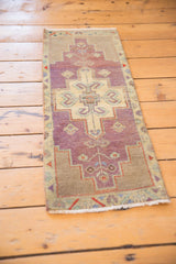 Elongated vines and geometric motifs in dusty purple and ivory on the distressed Oushak rug.