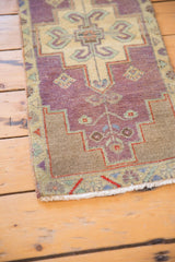 Distressed texture of the Oushak runner's dusty purple pile, ivory geometric patterns, and fringed end.