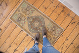 Distressed vintage Oushak runner's stepped diamond medallion and muted floral designs.