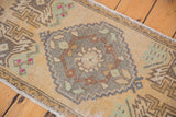 Distressed vintage Oushak runner, diamond medallion in beige, seafoam, silver, and pale bronze hues.