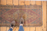 Distressed Oushak runner, its elongated geometric medallion in faded purple, sand, and ivory.