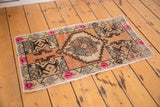 Oushak rug corner with vivid pink floral motifs, original selvage, and distressed texture.