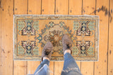 Worn gold corner of a distressed Oushak rug with oxidized green plant motif.
