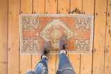 Section of vintage distressed Oushak rug with pale terra cotta and ivory geometric patterns.