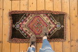 Distressed vintage Oushak rug corner, showing charcoal field, playful pink and teal geometric medallion.