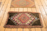 Distressed Oushak rug featuring a geometric medallion, blush mauve, bright pink, and teal.