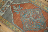 Burnt orange Oushak rug field with grey serrated medallion outline, blue motifs, and low pile.