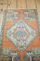 Distressed Oushak rug detail: faded burnt orange and ivory diamond medallion with germinating plant motif.