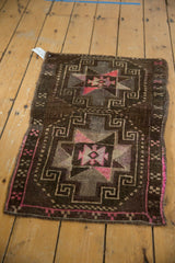 Distressed Oushak rug's lower right corner, showing bright pink edge and geometric patterns with texture.