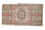 Distressed vintage Oushak rug with blush, ivory, raspberry geometric medallion, worn pile.