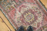 Distressed Oushak rug with mostly even wear, showing blush, raspberry, beige geometric motifs.