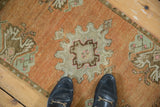 Distressed Oushak rug featuring a scalloped medallion, stylized motifs, and low terracotta pile.