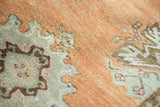 Visible low pile and stylized motifs on distressed Oushak rug in terracotta and ivory.