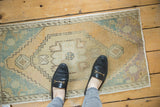 Distressed hand knotted Oushak rug's worn texture, peach, antique ivory, and mint green.