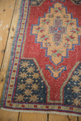 Distressed Oushak rug corner, cherry red and navy geometric motifs, with visible pile wear.