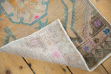 Folded corner of vintage Oushak rug, revealing reverse weave, distressed pile, and vivid motifs.