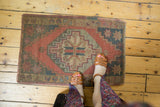 Geometric medallion, dusty blush, faded navy on distressed Oushak rug with even wear.