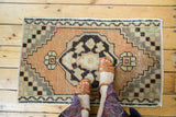 Distressed Oushak rug corner, showing checker pattern spandrel in sandalwood, charcoal, and sea foam.