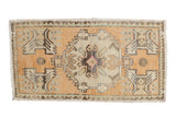 Distressed vintage Oushak rug mat in tangerine orange, ivory medallion, and stylized floral motifs.
