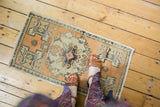 Corner of a distressed Oushak rug mat with tangerine, ivory, and charcoal geometric border.