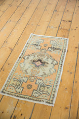 Distressed texture of the vintage Oushak rug, showing pale tangerine, ivory, and silver geometric motifs.