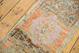 Distressed pile of Oushak rug mat with mauve medallion and terracotta floral motifs.
