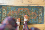 Distressed Oushak rug with abrashed terracotta field, slate blue medallion, and low pile.