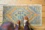 Distressed Turkish Oushak rug mat with faded gold and slate blue geometric patterns.
