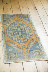 Distressed Oushak rug corner, geometric dark gold, slate blue-gray pattern, and worn texture.