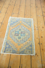 Distressed bottom corner of vintage Oushak rug, showing worn texture in blue and gold.