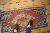 Distressed Oushak runner corner with cochineal red, apricot, and cobalt geometric patterns.