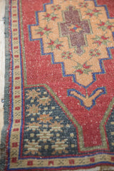 Detail of distressed Oushak runner corner with cochineal red, cobalt blue, apricot, and green motifs.