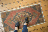 Distressed vintage Oushak rug texture, highlighting brick red, charcoal, and ivory serrated patterns.