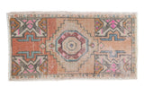 Distressed vintage Oushak hand-knotted rug mat with geometric medallion in terracotta, pink, blue.