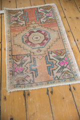 Distressed corner of Oushak rug displaying geometric patterns, hot pink, apricot, and intact selvage.