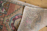 Distressed Oushak rug showing hand knotted foundation, even wear, and colorful motifs.