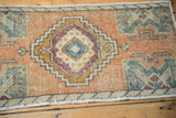 Close-up of distressed Oushak rug showing worn apricot field and slate blue-green geometric design.