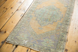 Worn texture of a distressed vintage Oushak rug with apricot gold and pistachio green.