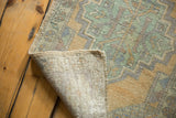 Distressed Oushak rug showing hand-knotted foundation, worn pistachio and gold pile, and original selvage.