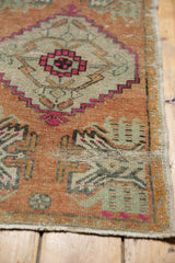 Apricot, seafoam, and fuchsia geometric patterns on a distressed vintage Oushak rug.