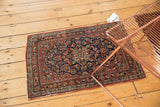 Vintage Kashan rug detail showing scrolling navy, cherry red floral blossoms and worn outer border.